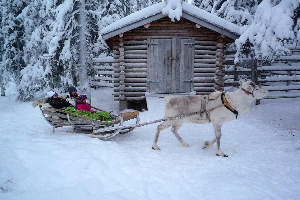 A reindeer sleigh passing a snowy log cabin in the forest